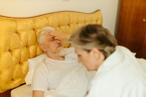 elderly man lying down on bed looking sick